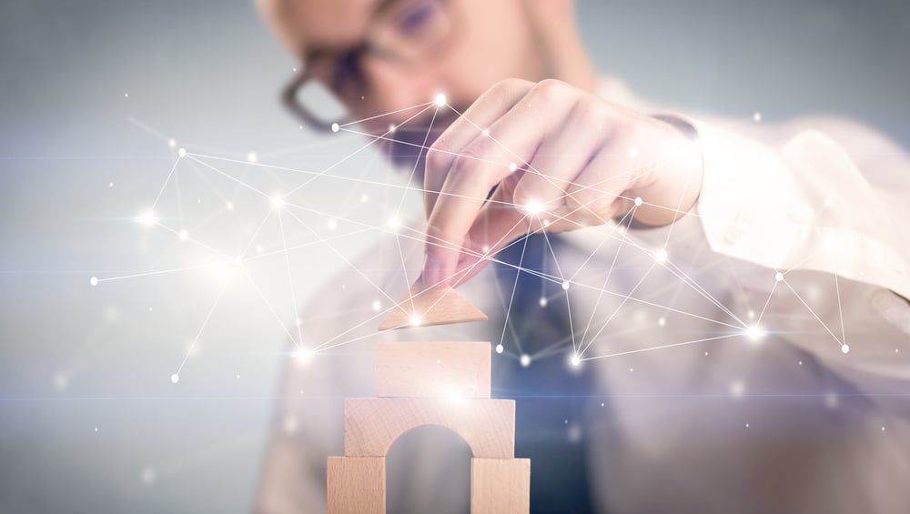 Young handsome businessman using wooden building blocks with interconnected lines and dots around him